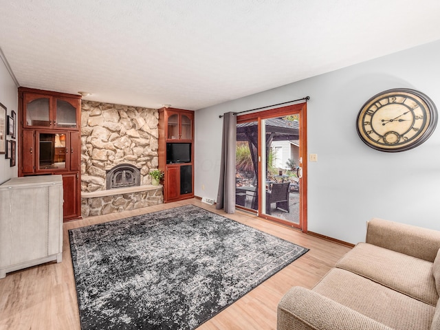 living room featuring light wood-type flooring and a stone fireplace