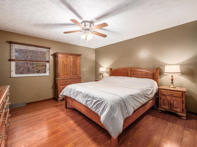 bedroom with hardwood / wood-style floors, a textured ceiling, and ceiling fan