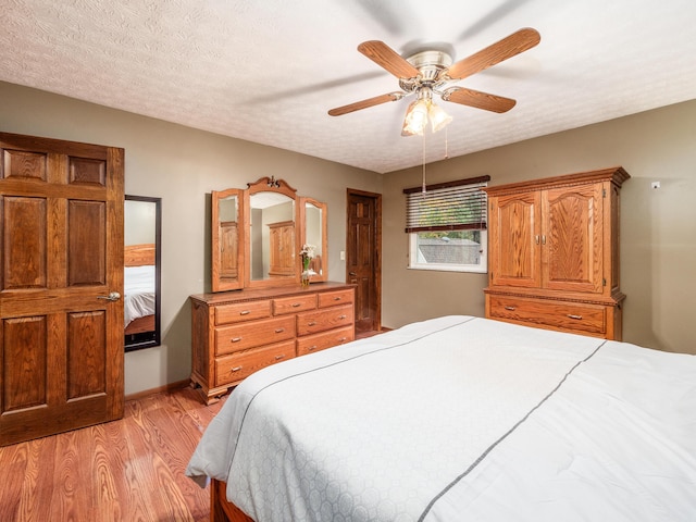 bedroom featuring ceiling fan, light hardwood / wood-style floors, and a textured ceiling