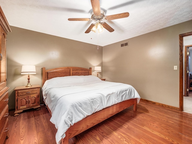 bedroom with hardwood / wood-style floors, a textured ceiling, and ceiling fan