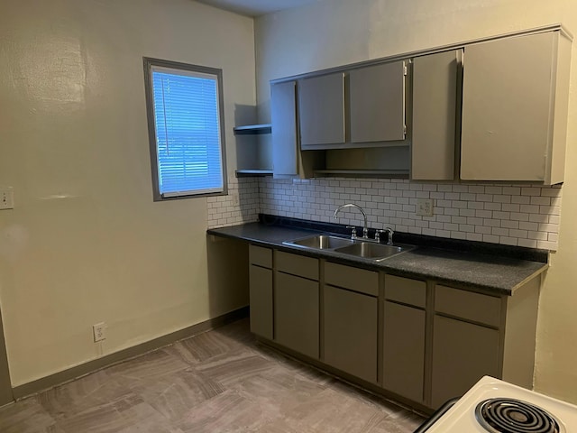 kitchen with gray cabinets, decorative backsplash, sink, and stove