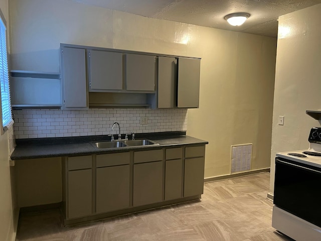 kitchen with white electric range oven, gray cabinets, decorative backsplash, and sink