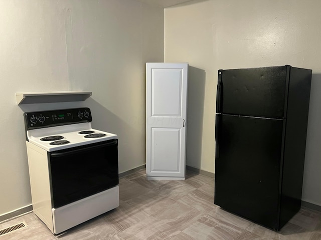 kitchen featuring white electric range, white cabinetry, and black fridge