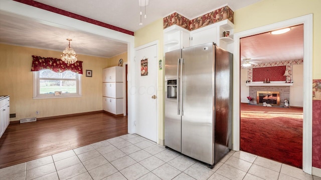 kitchen featuring light tile patterned flooring, white cabinetry, stainless steel refrigerator with ice dispenser, and hanging light fixtures