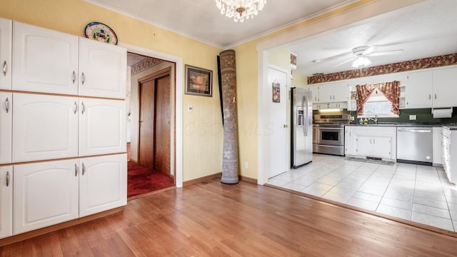 kitchen featuring stainless steel appliances, crown molding, sink, light hardwood / wood-style flooring, and white cabinetry