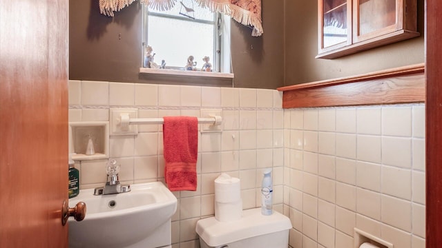 bathroom with toilet, tile walls, and sink