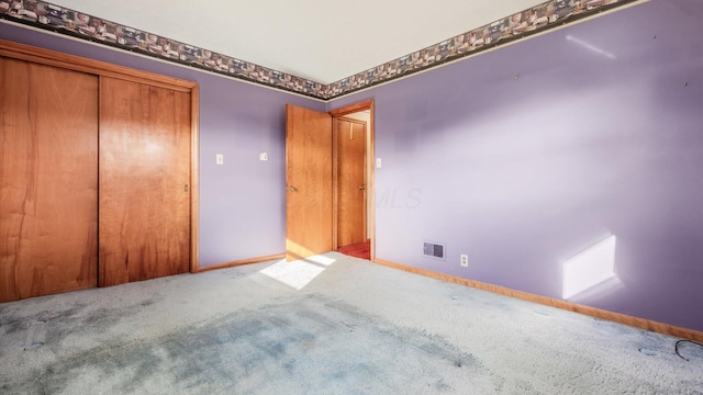 unfurnished bedroom featuring light carpet and a closet