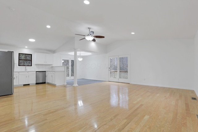 unfurnished living room with a healthy amount of sunlight, ceiling fan, light hardwood / wood-style floors, and vaulted ceiling