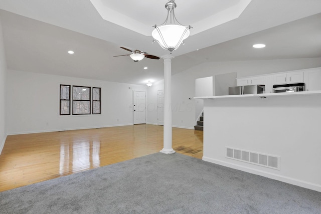 unfurnished living room with light colored carpet, ornate columns, and ceiling fan