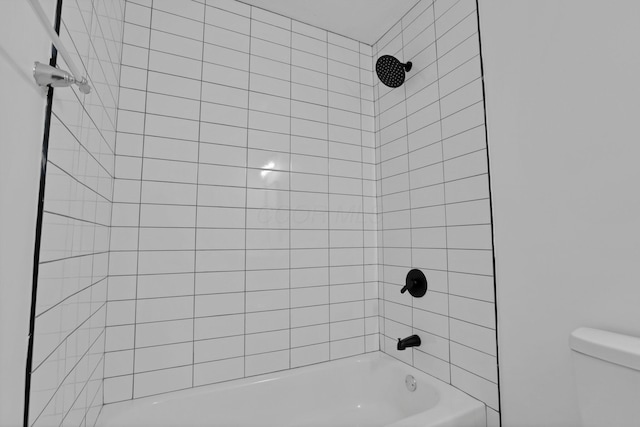 bathroom with toilet and tiled shower / bath