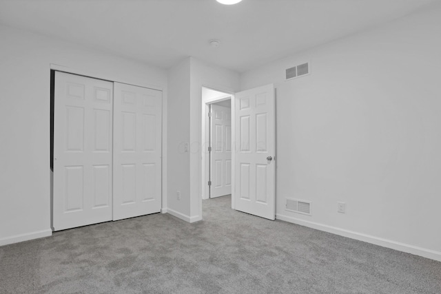 unfurnished bedroom featuring light colored carpet and a closet