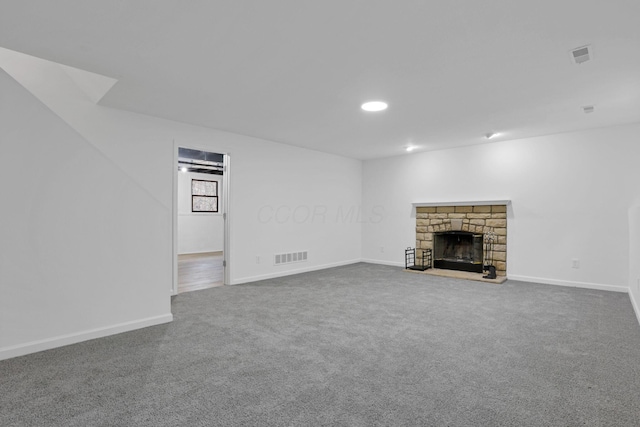 unfurnished living room featuring carpet flooring and a stone fireplace