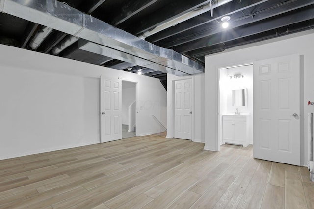 basement featuring sink and light hardwood / wood-style flooring