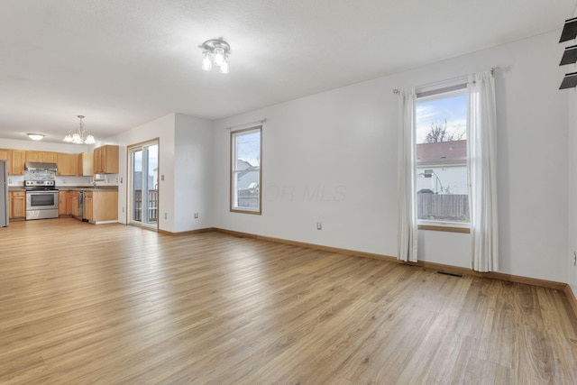 unfurnished living room featuring a chandelier and light wood-type flooring