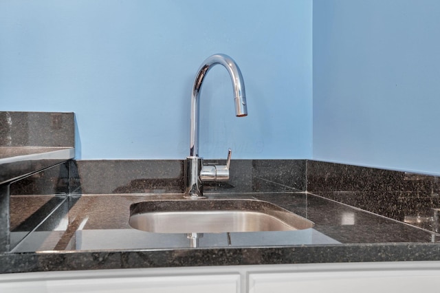 room details with white cabinets, dark stone countertops, and sink