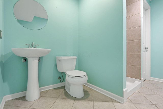 bathroom with tiled shower, tile patterned flooring, and toilet