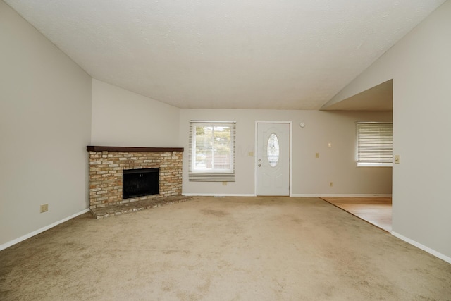 unfurnished living room with light carpet, a fireplace, vaulted ceiling, and a textured ceiling