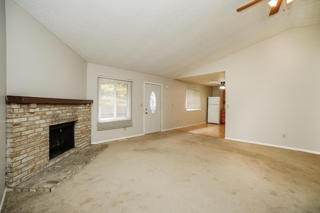 unfurnished living room featuring light carpet, a brick fireplace, lofted ceiling, and ceiling fan