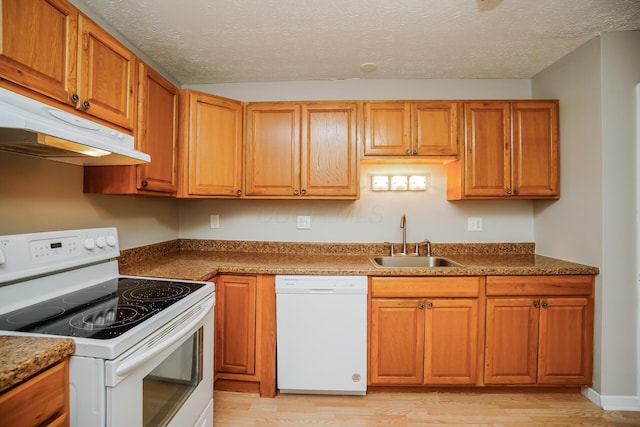 kitchen with sink, white appliances, light hardwood / wood-style flooring, and a textured ceiling