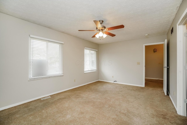 carpeted spare room with a textured ceiling and ceiling fan