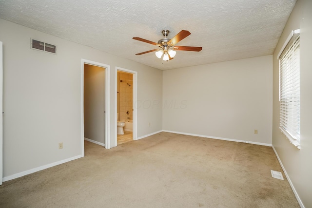 empty room with plenty of natural light, light carpet, a textured ceiling, and ceiling fan