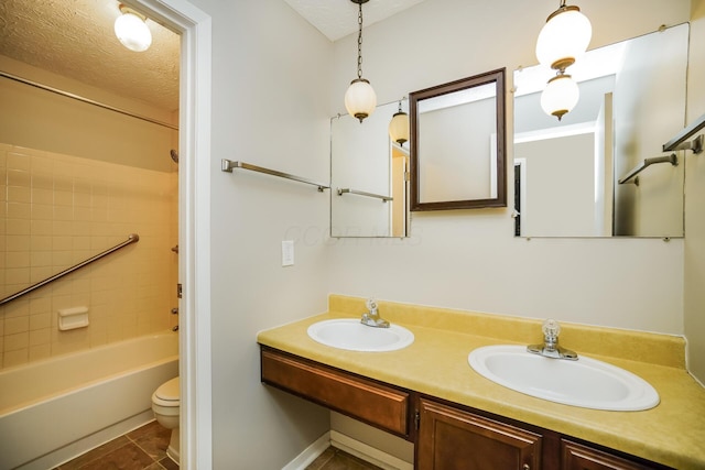 full bathroom with tiled shower / bath, vanity, a textured ceiling, and toilet