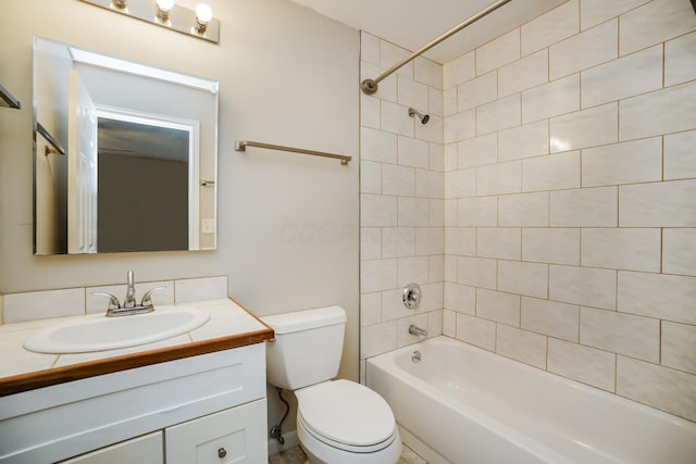 full bathroom with tiled shower / bath, vanity, and toilet