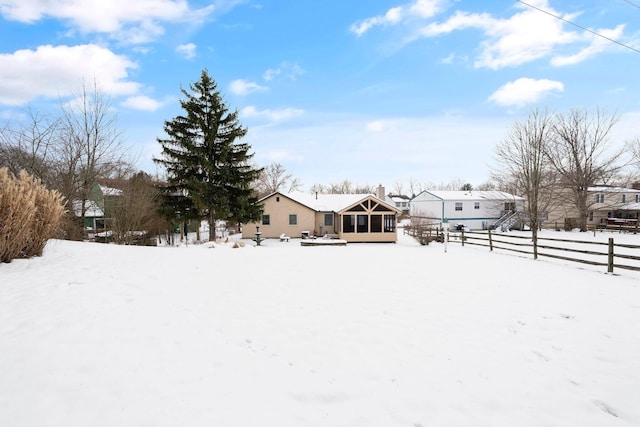 yard layered in snow featuring a sunroom