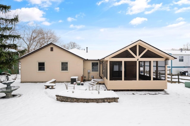 snow covered rear of property featuring central AC and a sunroom