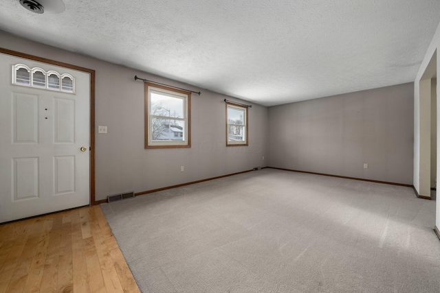 foyer with a textured ceiling and light wood-type flooring