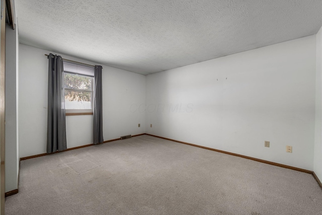 spare room featuring a textured ceiling and light colored carpet