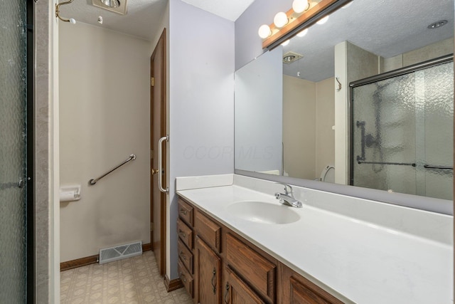 bathroom featuring a textured ceiling, walk in shower, and vanity