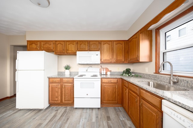 kitchen featuring light stone countertops, sink, white appliances, and light wood-type flooring