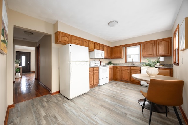 kitchen featuring sink, light hardwood / wood-style floors, and white appliances