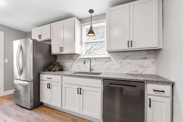 kitchen with sink, stainless steel appliances, light hardwood / wood-style floors, decorative light fixtures, and white cabinets