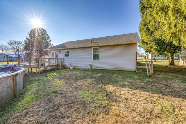 rear view of property with a pool side deck and a lawn