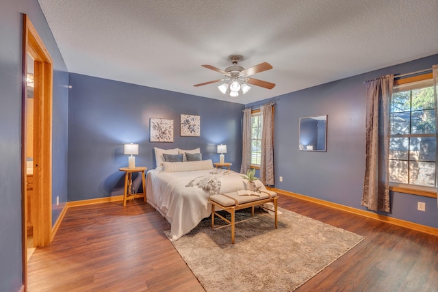 bedroom featuring ceiling fan, dark hardwood / wood-style floors, and multiple windows