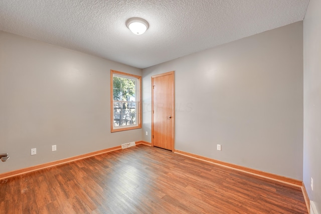 spare room featuring a textured ceiling and light hardwood / wood-style flooring