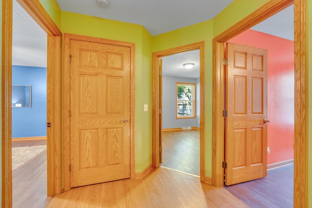 hall featuring a textured ceiling and light wood-type flooring