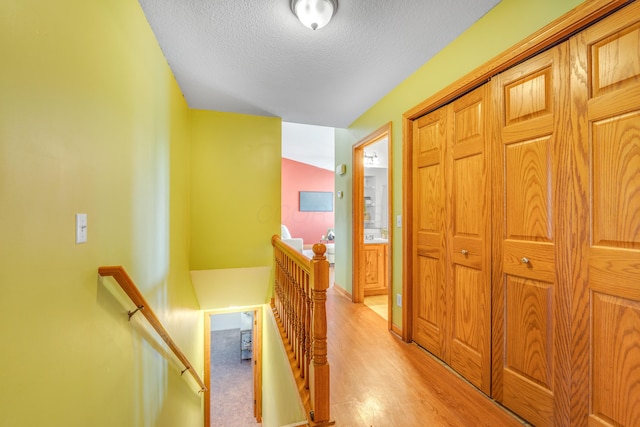 corridor with light hardwood / wood-style floors and a textured ceiling