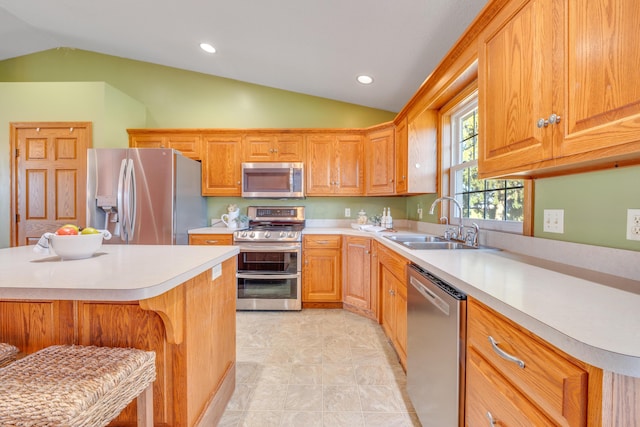 kitchen with a breakfast bar, sink, appliances with stainless steel finishes, and vaulted ceiling