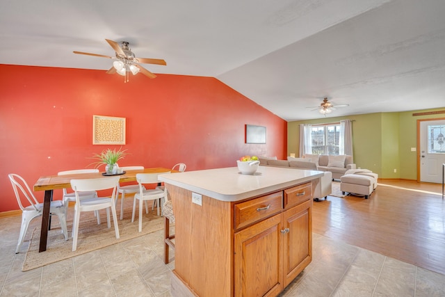 kitchen featuring ceiling fan, a center island, light hardwood / wood-style floors, lofted ceiling, and a breakfast bar