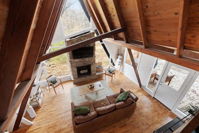 living room with wooden ceiling, high vaulted ceiling, light hardwood / wood-style flooring, a fireplace, and beamed ceiling