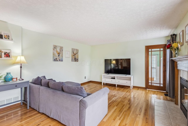 living room featuring a textured ceiling, a fireplace, and light hardwood / wood-style floors