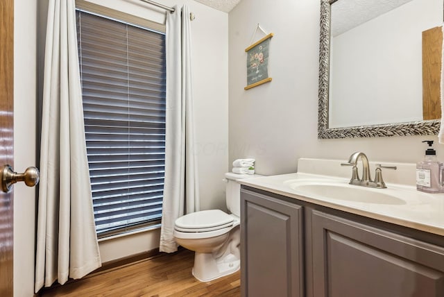 bathroom with vanity, toilet, wood-type flooring, and a textured ceiling