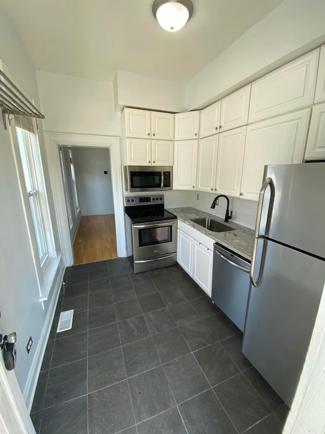 kitchen featuring light stone counters, sink, white cabinets, and stainless steel appliances