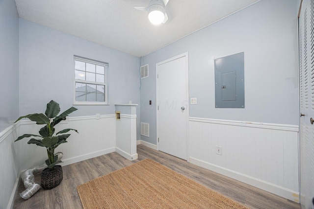 foyer entrance with hardwood / wood-style floors, a textured ceiling, and electric panel