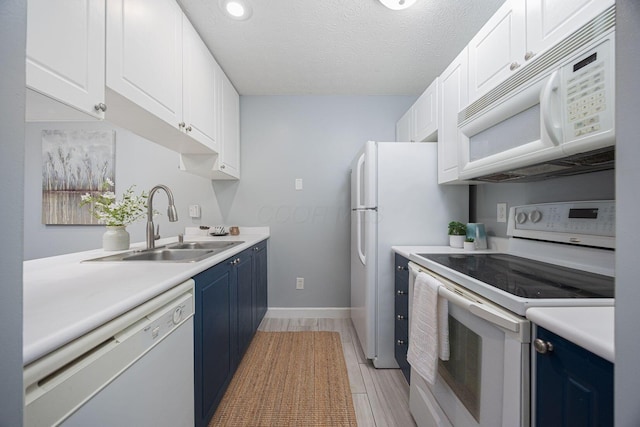 kitchen featuring white appliances, white cabinets, sink, blue cabinetry, and a textured ceiling