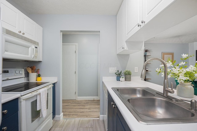 kitchen featuring white cabinetry, sink, blue cabinets, a textured ceiling, and white appliances