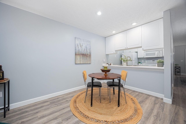 dining space featuring light wood-type flooring and a textured ceiling